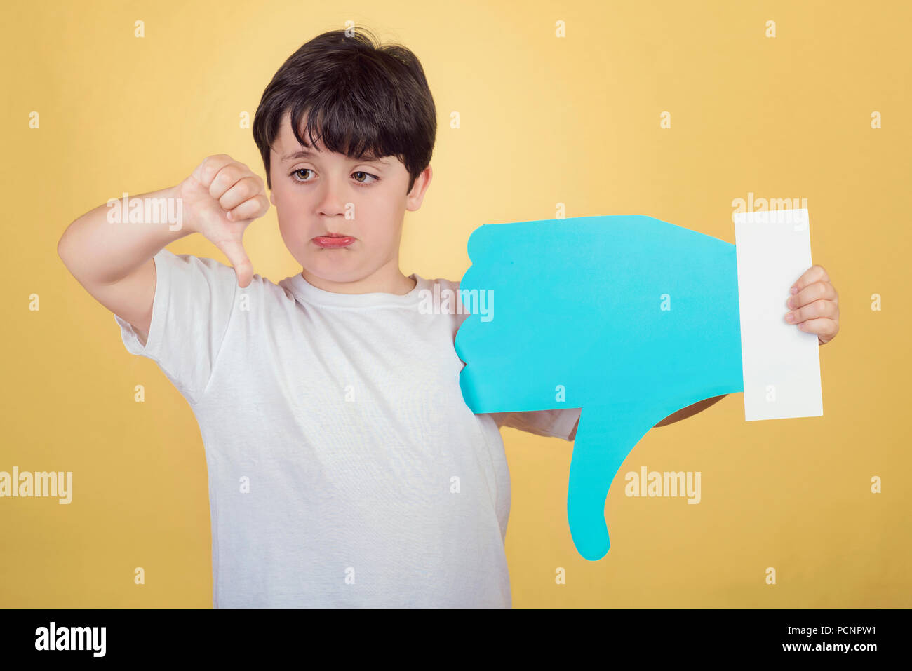 Junge Holding eine Abneigung Symbol auf gelbem Hintergrund Stockfoto