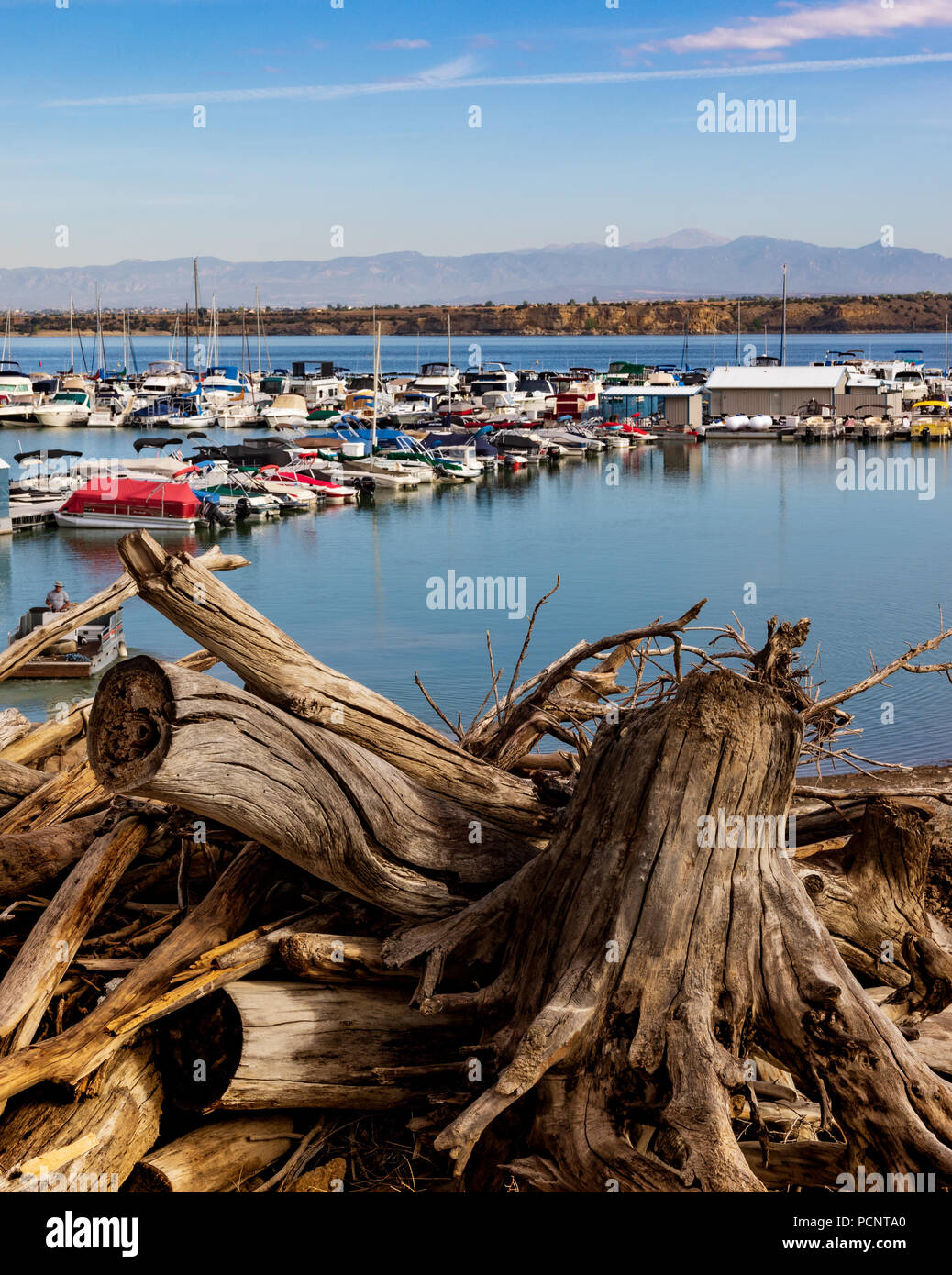 PUEBLO, CO, USA-16 Juli 18: Interessante Durcheinander von treibholz im Vordergrund, mit bunten Boote auf dem See Pueblo. Dunstige Berge im Hintergrund. Stockfoto