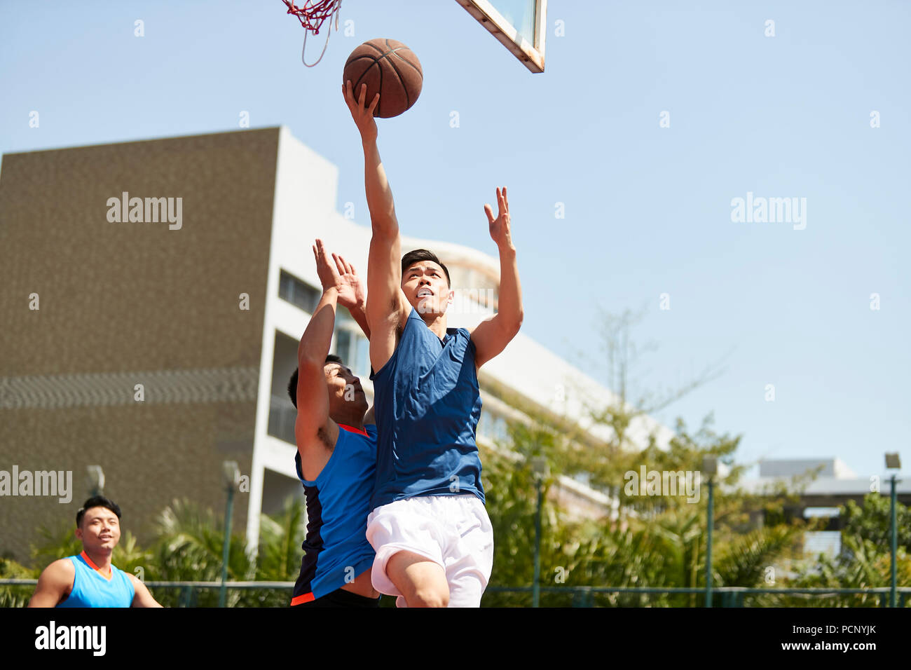 Jungen asiatischen Basketball Spieler gehen, für ein layup während Gegner spielen Verteidigung. Stockfoto