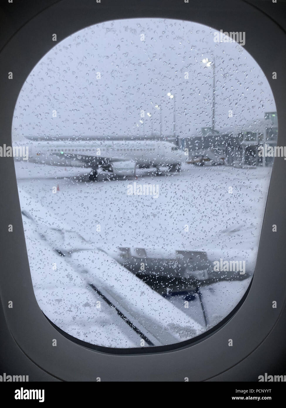 Flugzeug am Flughafen München bei Schneewetter, fotografiert von Bord Fenster Stockfoto