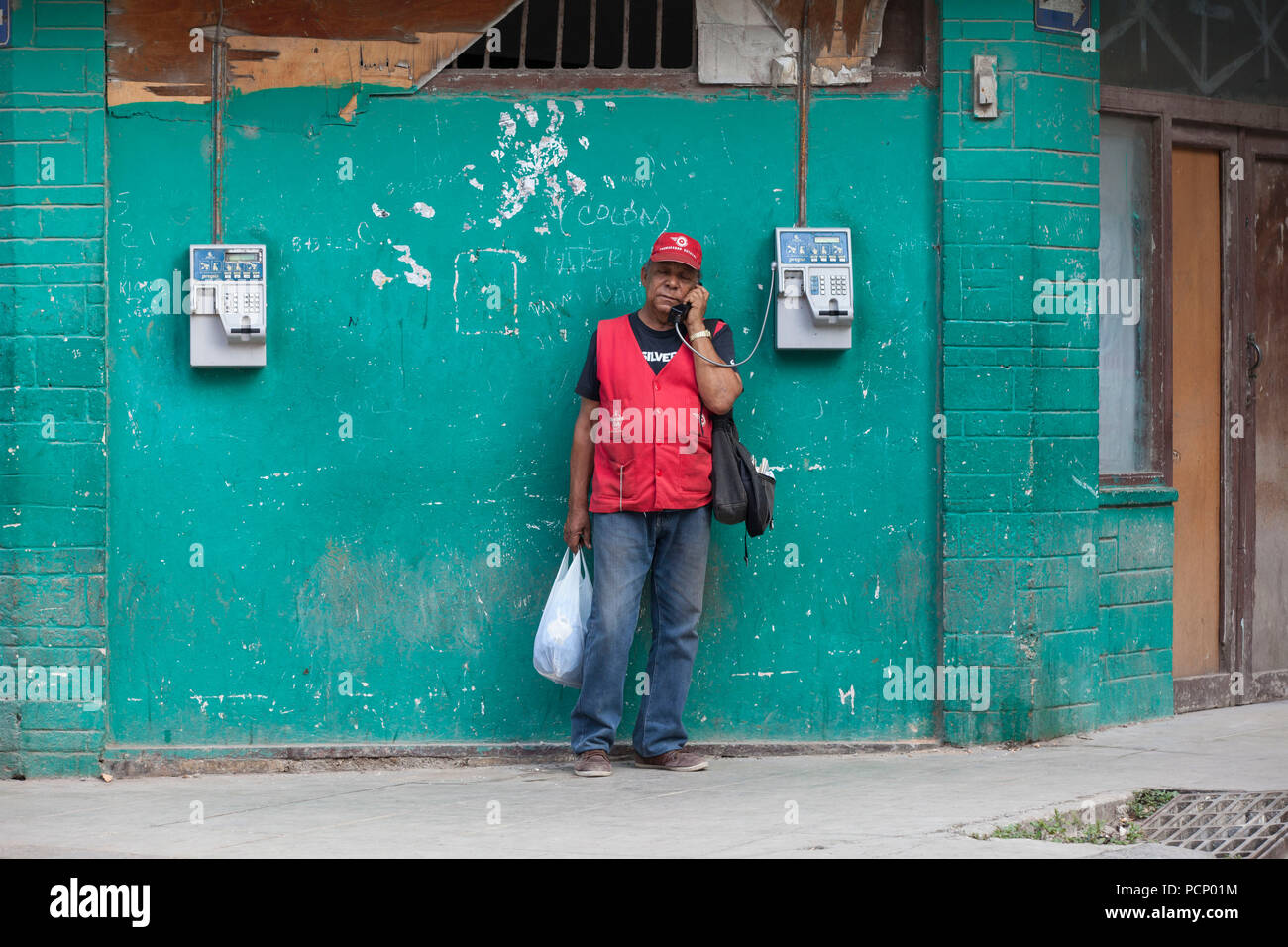 Karibik, Kuba, Havanna, Mann am Telefon vor Grün Außenwand Stockfoto