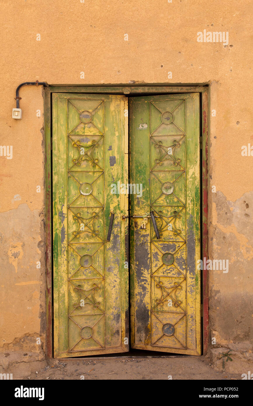 Oman, Al Hamra, grün-gelbe Metall Tür an ockerfarbene Hausfassade Stockfoto