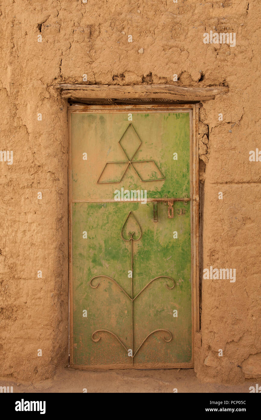 Oman, Al Hamra, grün-gelbe Metall Tür an ockerfarbene Hausfassade Stockfoto
