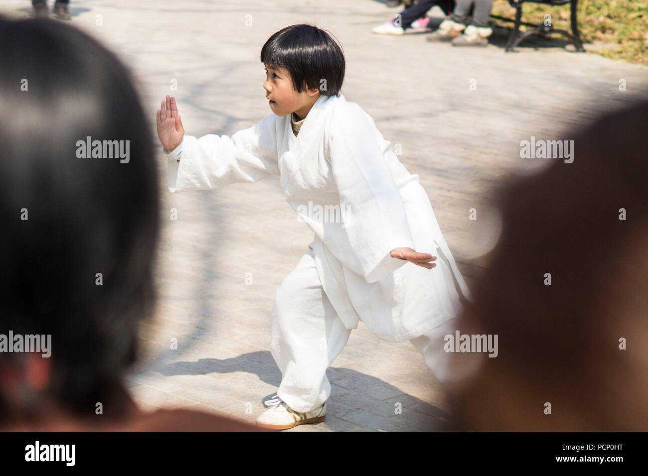 Ein Junge üben Qigong in der Mitte einer Gruppe von Menschen in Nanjing, China Stockfoto
