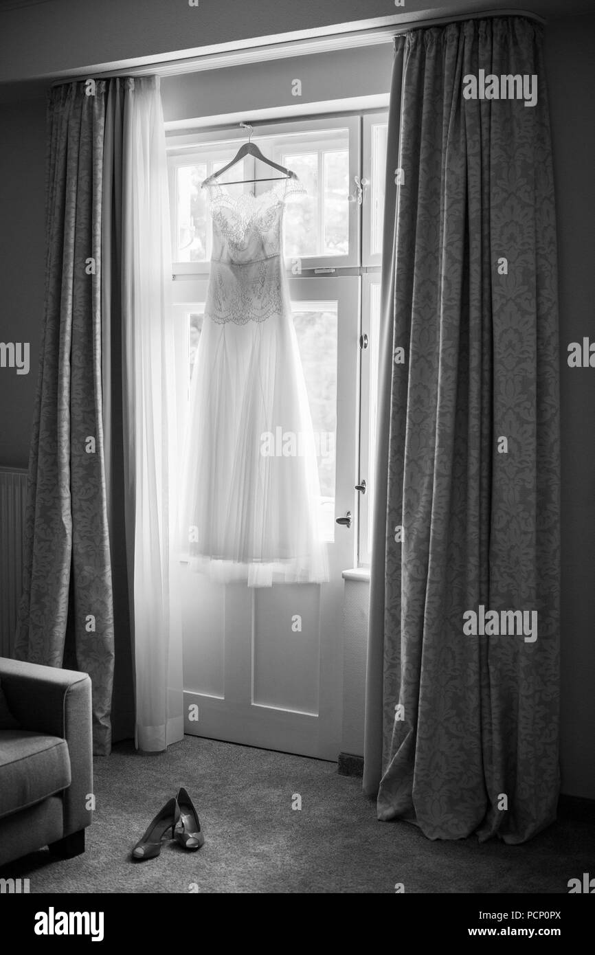 Hochzeit Kleid hängen am Fenster, Schuhe auf dem Boden, b/w Stockfoto