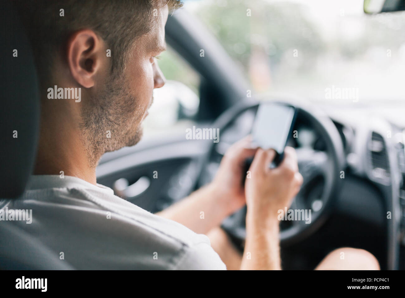 Unachtsame Fahrer über sein Handy während der Fahrt ein Auto Stockfoto
