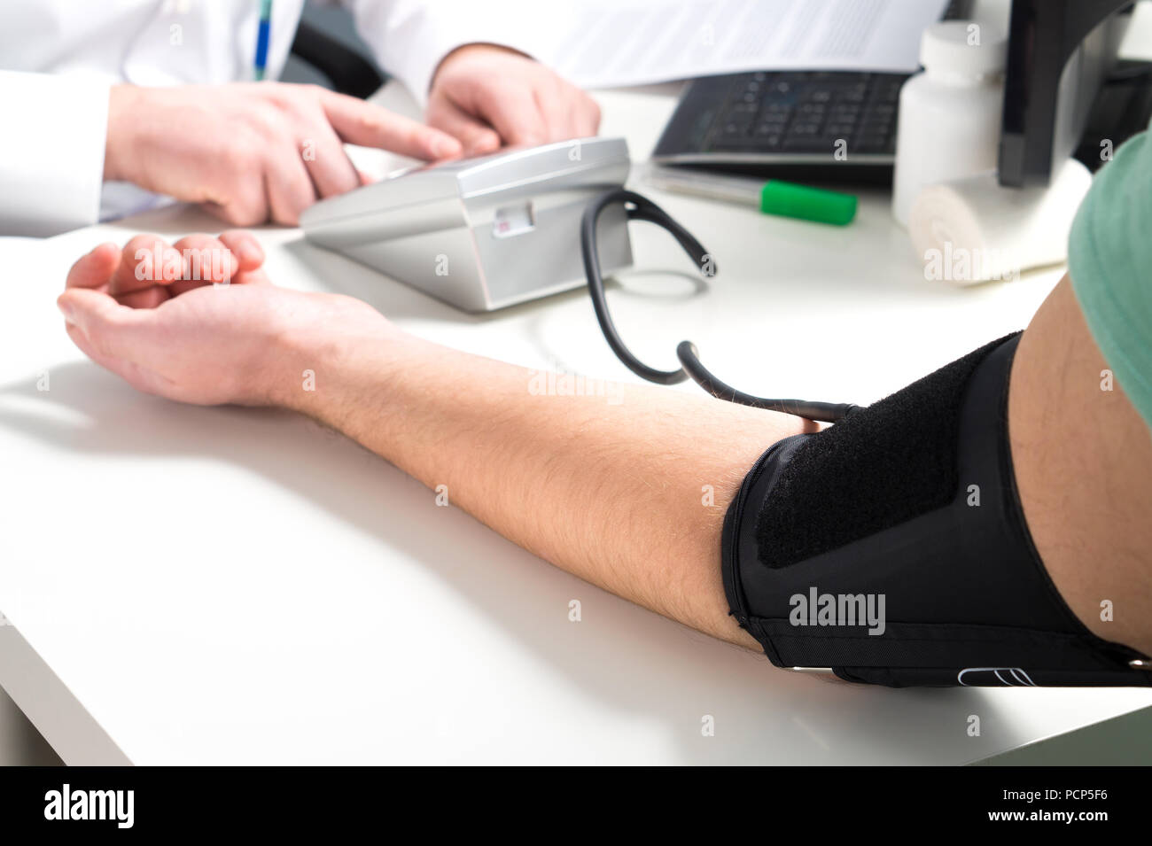 Arzt oder Krankenschwester messen Blutdruck eines Patienten mit Zähler und Geräte überwachen. Hand und Arm auf der Notaufnahme oder Krankenhaus Büro Tisch. Stockfoto