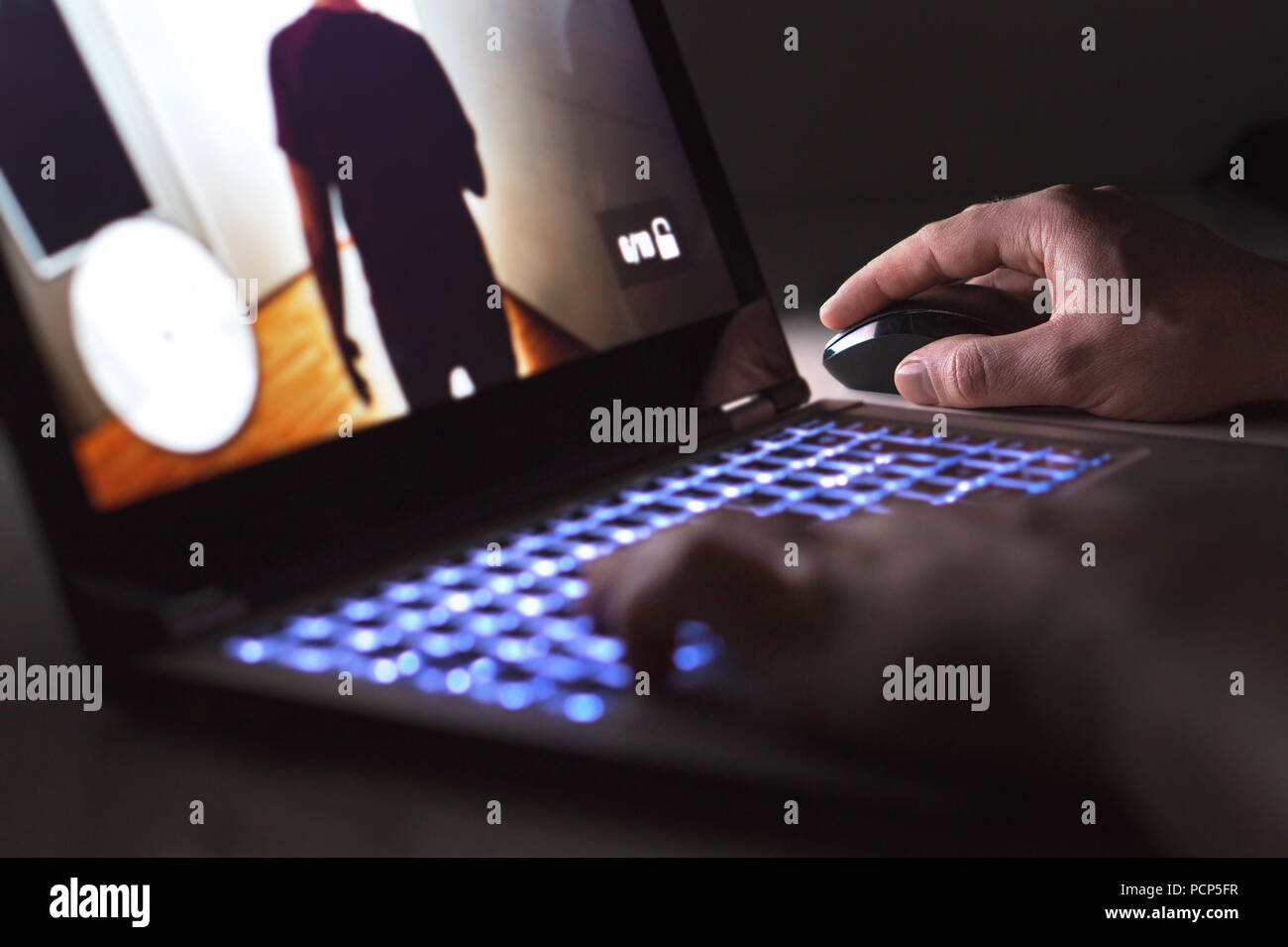 Junge Mann spielt Videospiel mit Laptop. Gamer mit Computer in dunklen oder spät in der Nacht. Hände auf Maus und Tastatur. Stockfoto