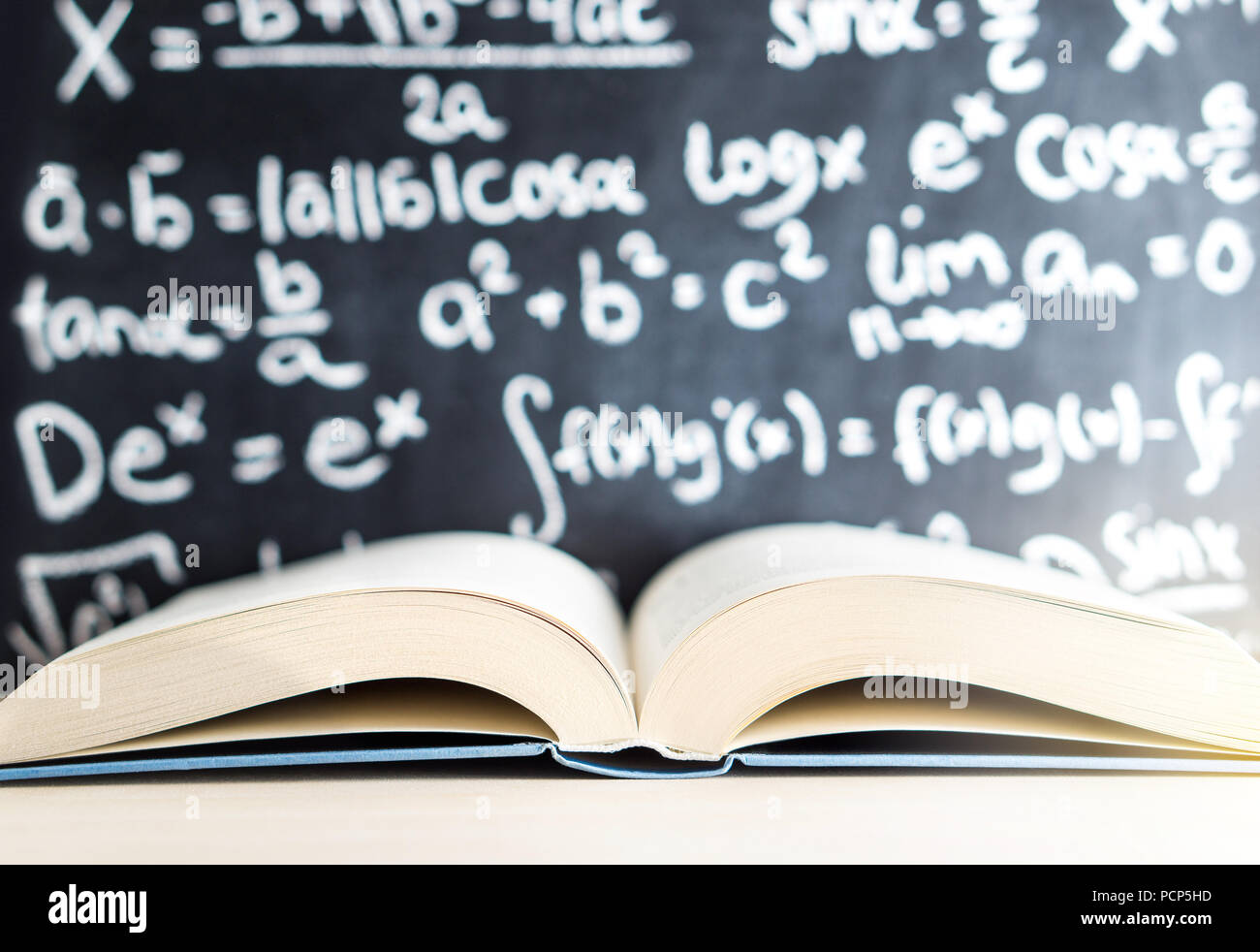 Wissen, Bildung, Mathematik, Wissenschaft und Weisheit. Buchen Sie geöffnet vor einer Tafel und Schwarzes Brett voller Mathematik schreiben. Stockfoto