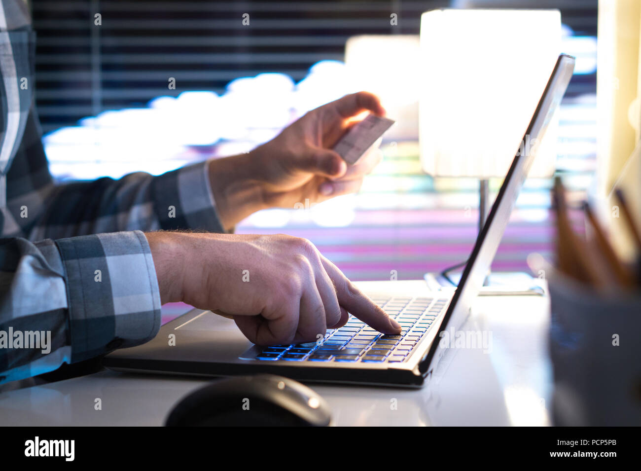 Online Einkaufen und Bezahlen mit Kreditkarte und Laptop. Mann kauft auf einem Internet store in modernen Home Office spät in der Nacht. Eingabe von Anmeldeinformationen Stockfoto