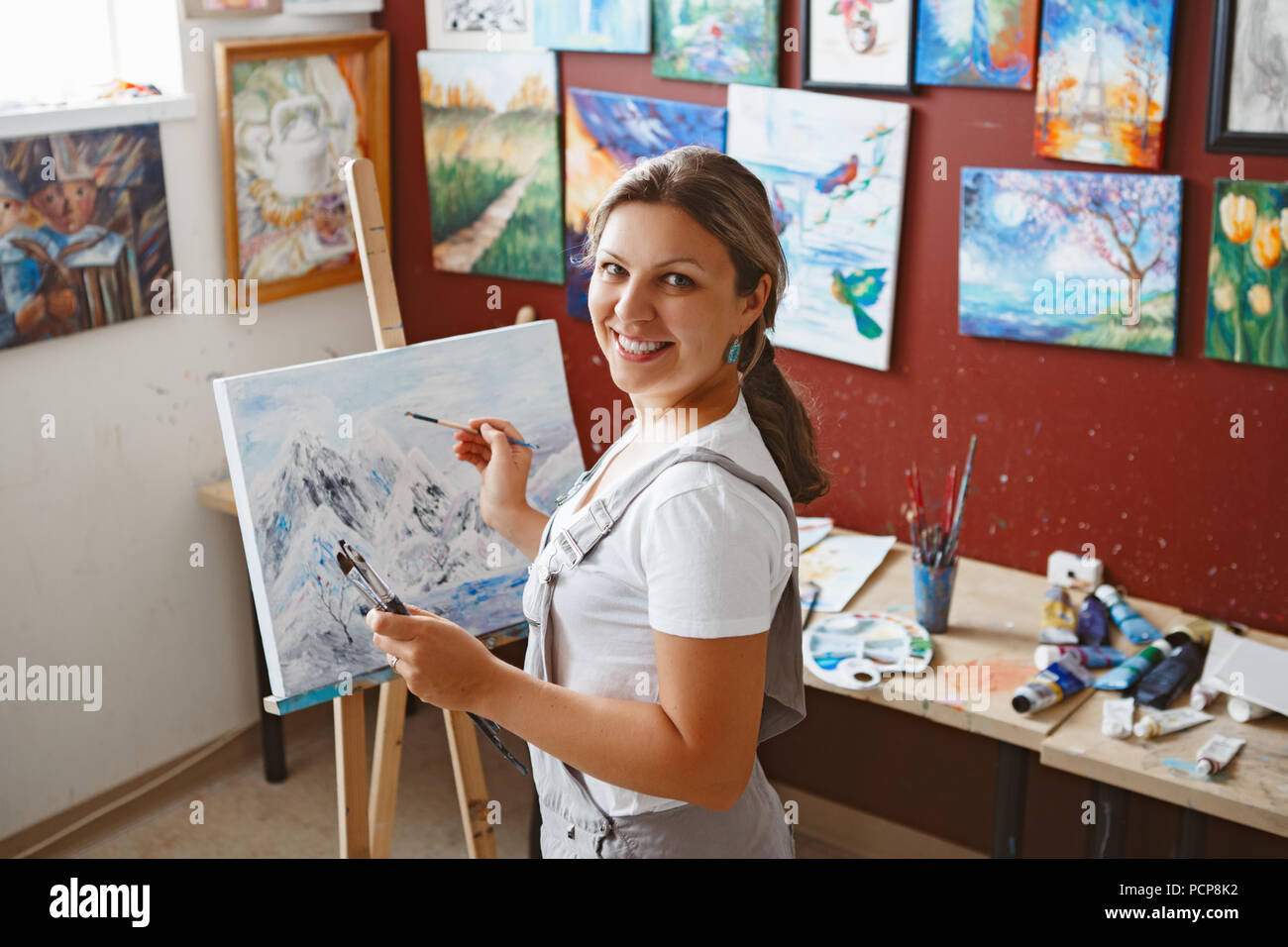 Porträt der jungen schönen mittleren Alter weiße Kaukasier Künstlerin Zeichnung Malerei im Atelier mit Acrylfarben auf Leinwand. Lebensweise Aktivität Stockfoto