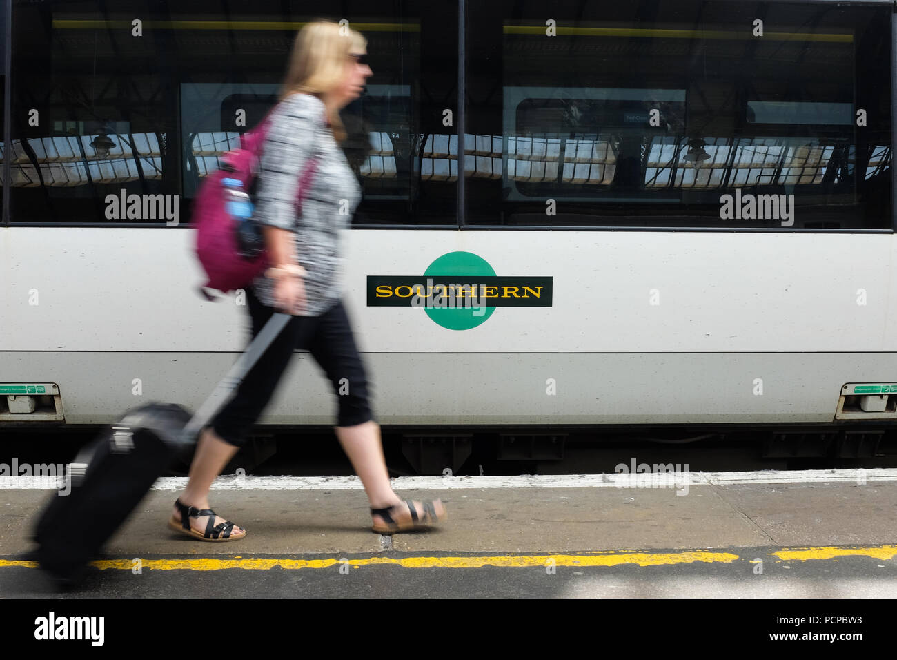 Ein Passagier zu Fuß vorbei an einem südlichen Waggon am Bahnhof in Brighton in England. Stockfoto