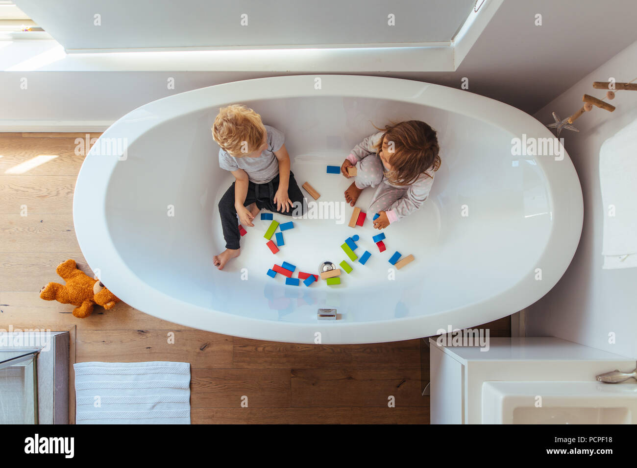 Blick von oben der Geschwister sitzen in der Badewanne mit Holz unterbauen. Kleinen Jungen und Mädchen spielen in einer Badewanne zu Hause. Stockfoto