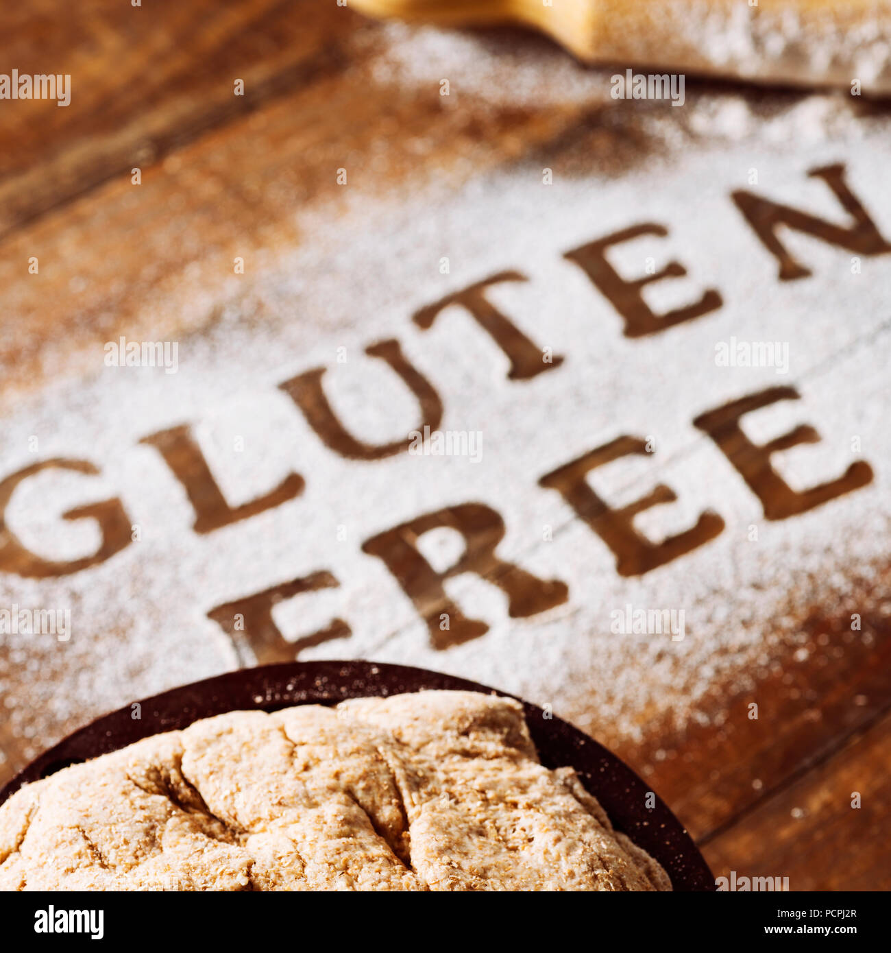 Nahaufnahme von einem Holztisch mit einem Glutenfreies Mehl, wo Sie den Text glutenfrei, neben einem nudelholz und ein Stück Teig lesen können Stockfoto