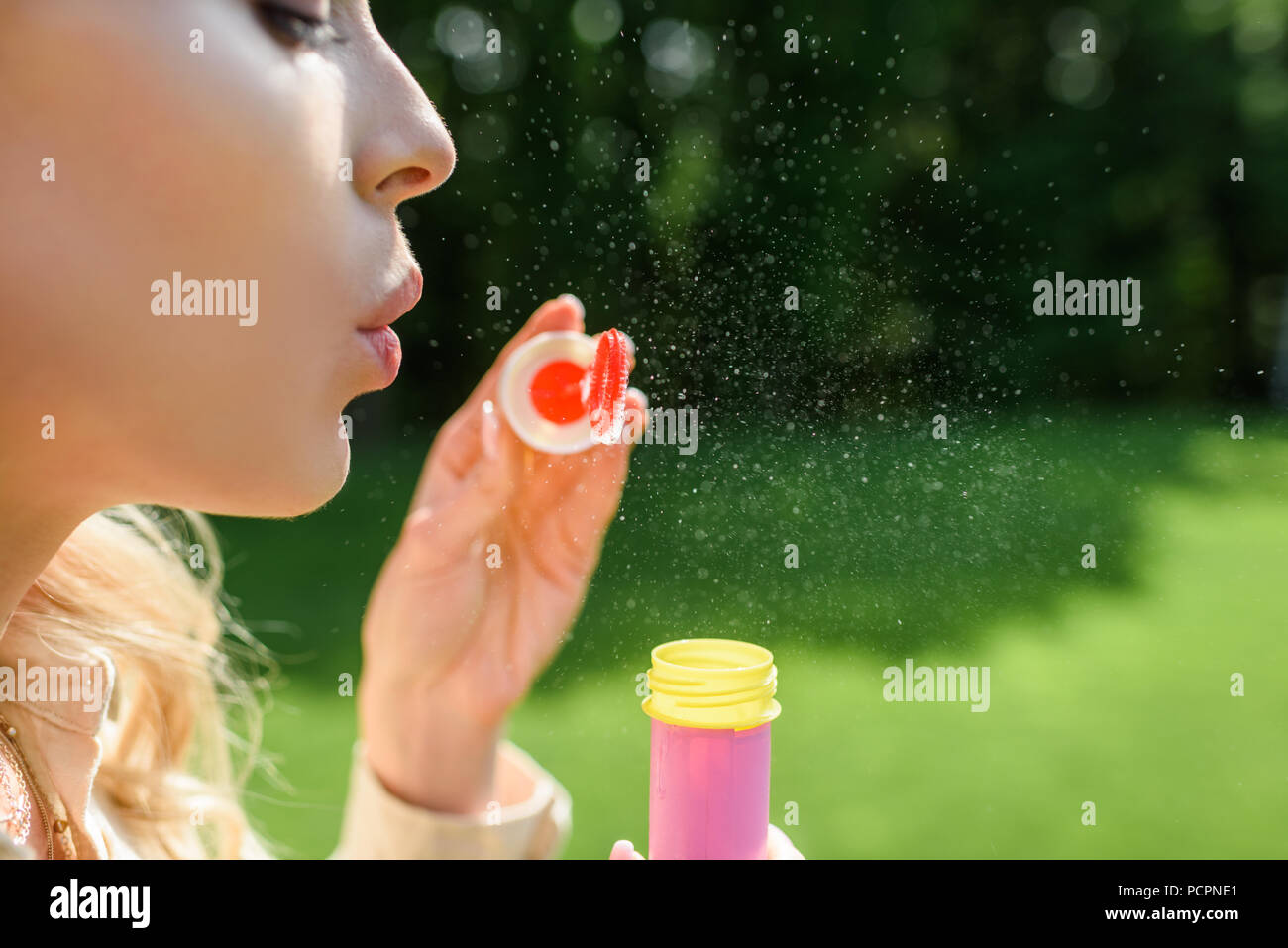 Seitenansicht der jungen Frau bläst Seifenblasen in Park Stockfoto
