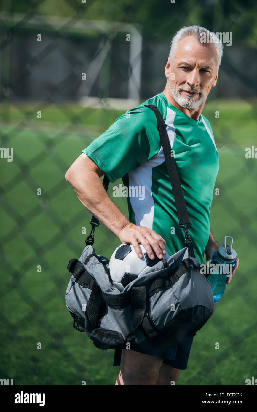 Seitenansicht des alten Mann mit sportlicher Wasserflasche und Tasche auf Fußball-Feld Stockfoto