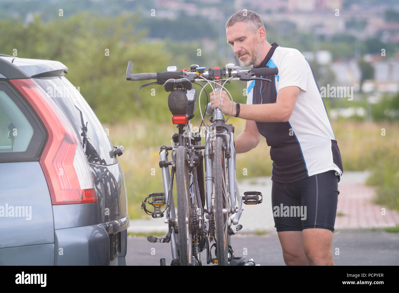 Mann, Sportswear laden Fahrräder auf dem Bike Rack zu einem Auto Anhängerkupplung montiert Stockfoto