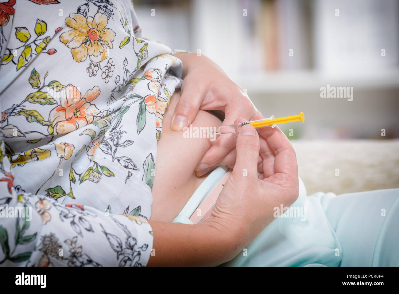 Frau tut ein Insulin oder Heparin Spritzen in ihrem Bauch zu Hause Stockfoto