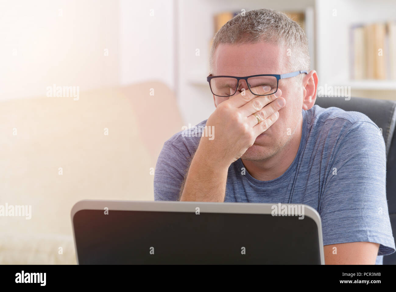 Müde Freiberufler Mann reibt sein Auge während der Arbeit mit dem Laptop Stockfoto