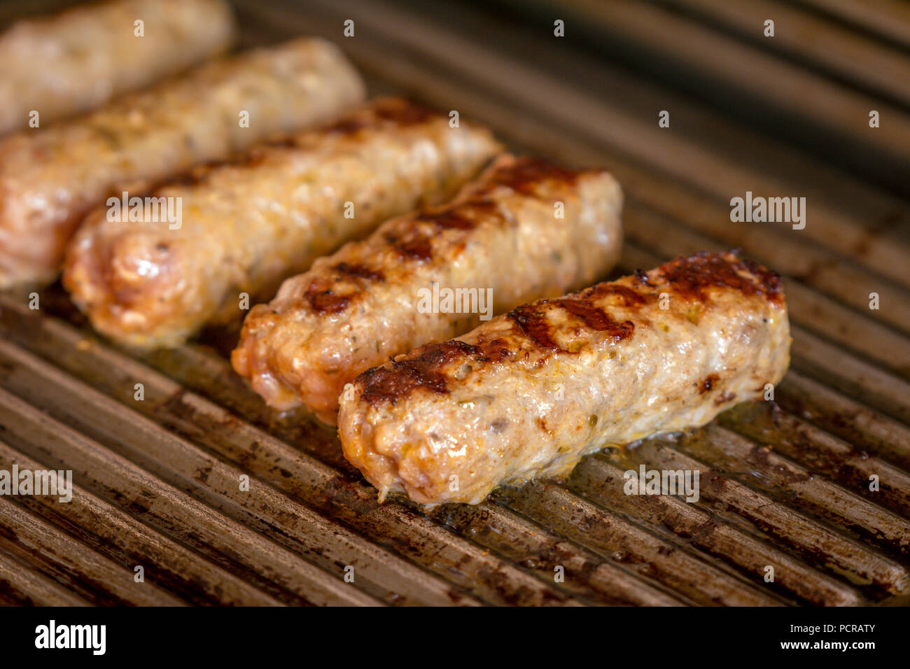 Cevapcici gebacken auf dem Grill. Kleine Würstchen aus Hackfleisch/Faschiertem, ein sehr beliebtes Gericht in den Balkanländern. Stockfoto