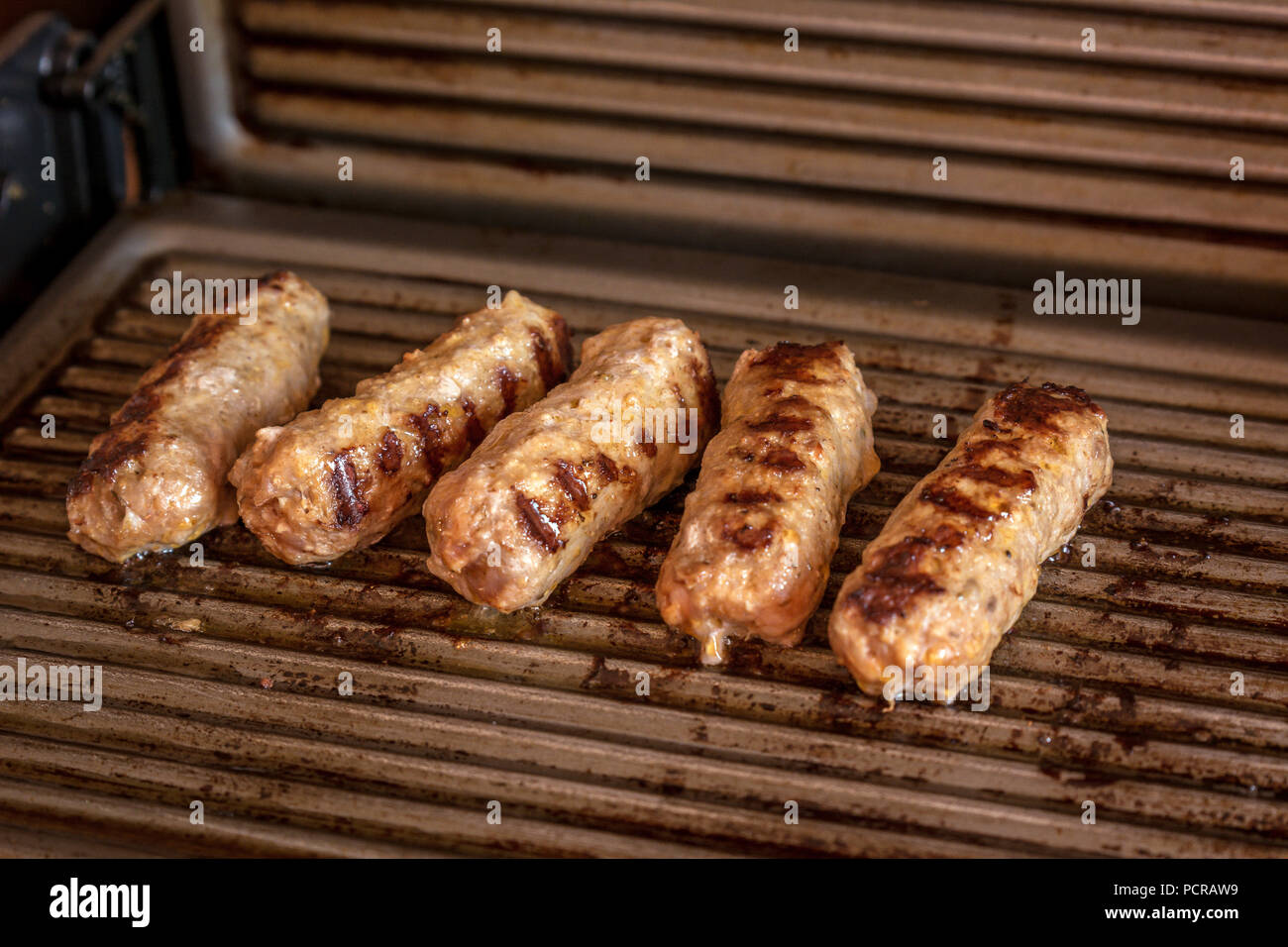 Cevapcici gebacken auf dem Grill. Kleine Würstchen aus Hackfleisch/Faschiertem, ein sehr beliebtes Gericht in den Balkanländern. Stockfoto