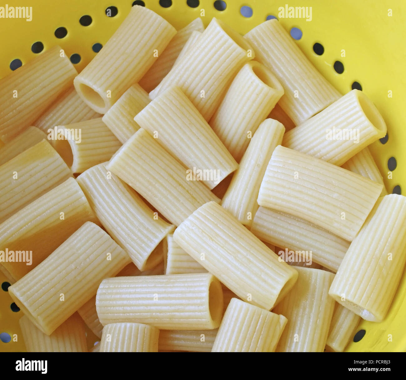 Abgelassen und gekochten Rigatoni Nudeln in einem gelben Kunststoff Sieb Stockfoto