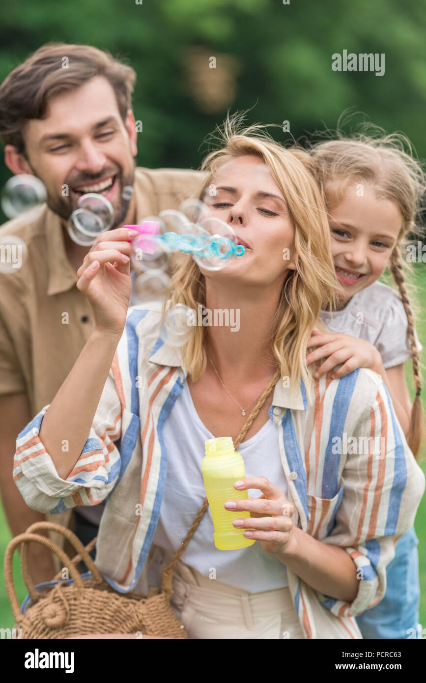 Glückliche Familie mit einem Kind bläst Seifenblasen in Park Stockfoto