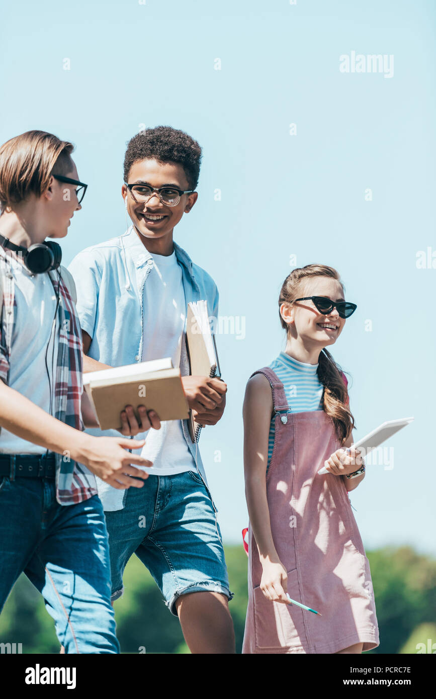 Smiling teenage Studenten mit Büchern und digitalen Tablet zusammen wandern in Park Stockfoto