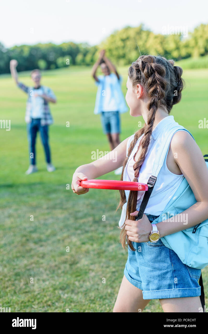 Schönes junges Mädchen werfen Flying Disc zu Freunden in Park Stockfoto