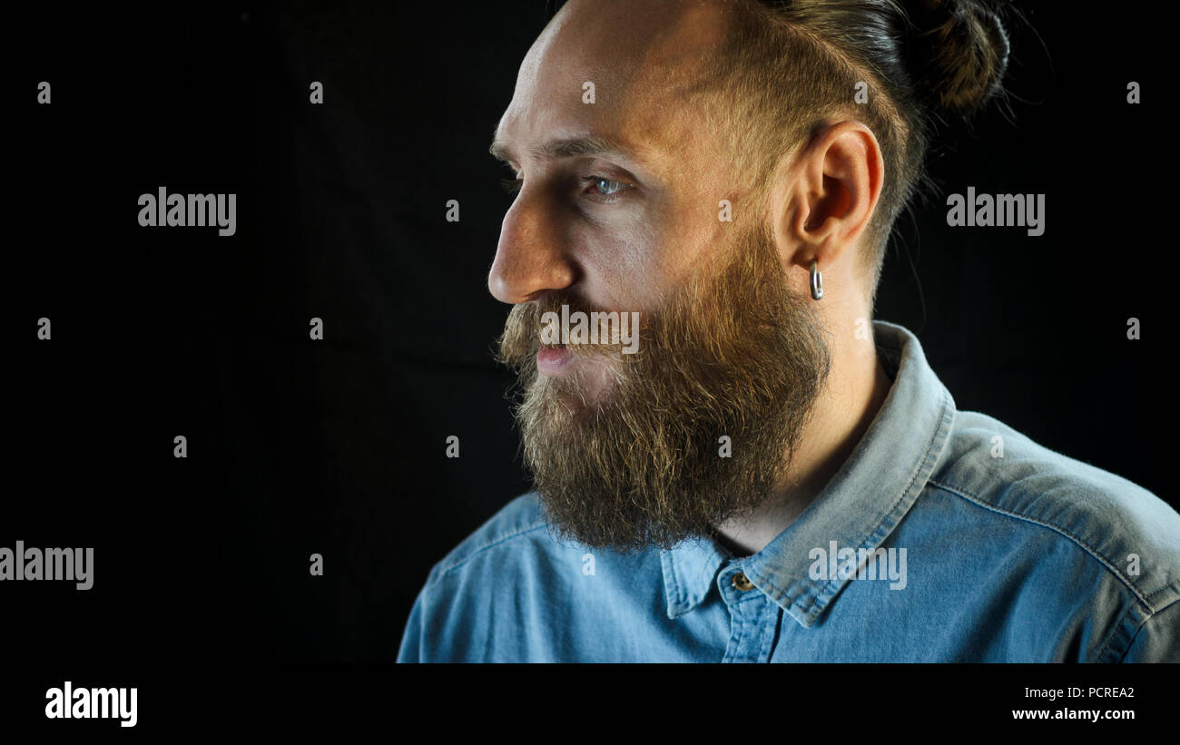 Portrait von bärtigen Mann in ein blaues Jeanshemd auf schwarzem Hintergrund. Stockfoto