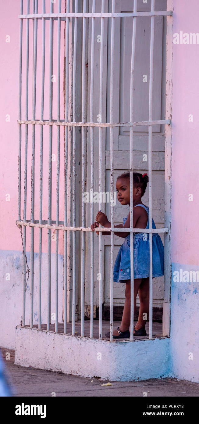 Kleine bunte Mädchen hinter Fenster Gitter in einem rosa Haus, Straße von Trinidad, Kuba, Sancti Spíritus, Kuba Stockfoto