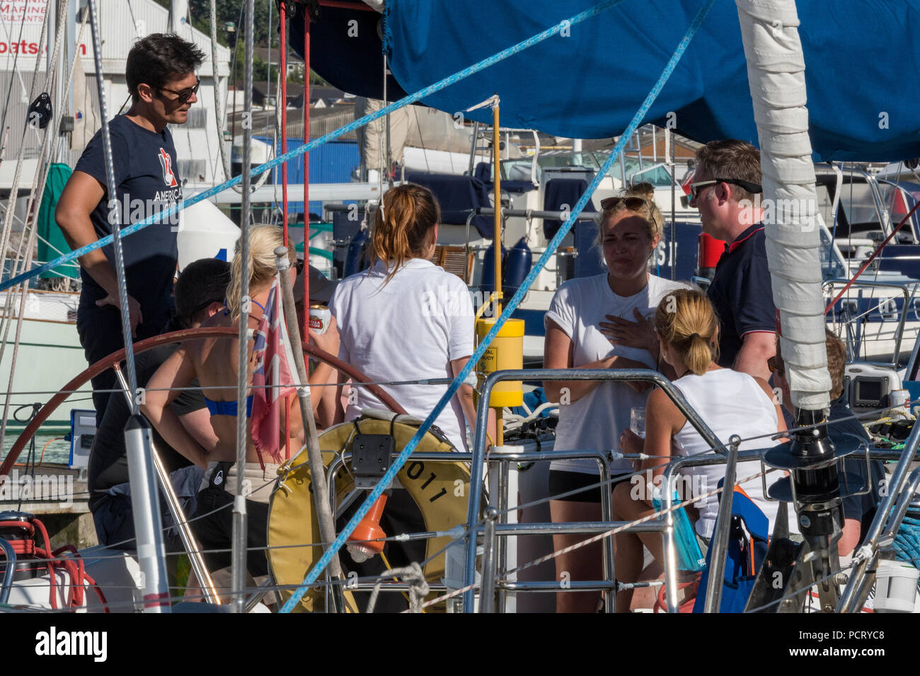 Eine Crew in Cowes Yacht Haven während der jährlichen Cowes Week Regatta auf der Insel Wight an einem crewing Briefing auf einem Racing Yacht segeln Boot informiert wird. Stockfoto