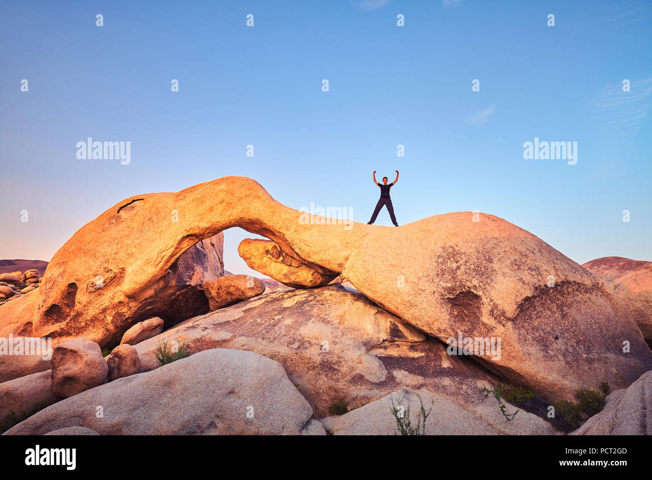 Einzigartige Felsformationen im Joshua Tree National Park mit weiblichen Kletterer bei Sonnenuntergang, Kalifornien, USA. Stockfoto