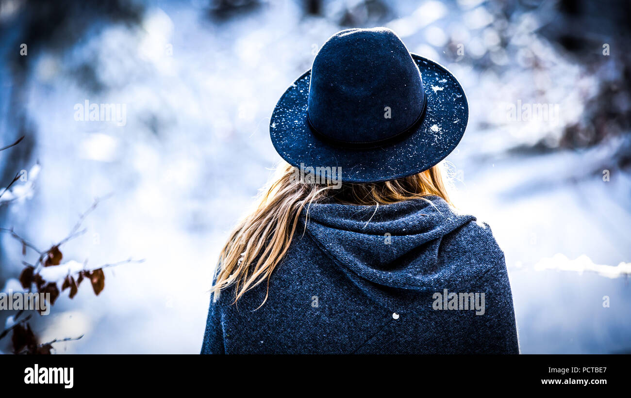 Junge Frau mit Hut und blondes Haar, Blick nach hinten, im Winter Stockfoto