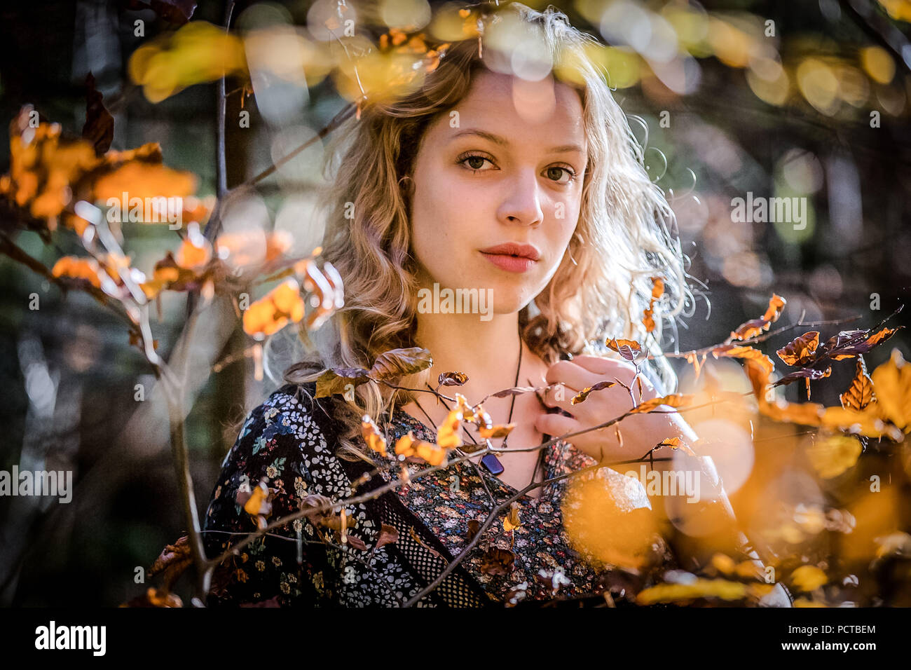 Junge Frau mit blondem Haar im Wald, ernsten und nachdenklichen Blick Stockfoto