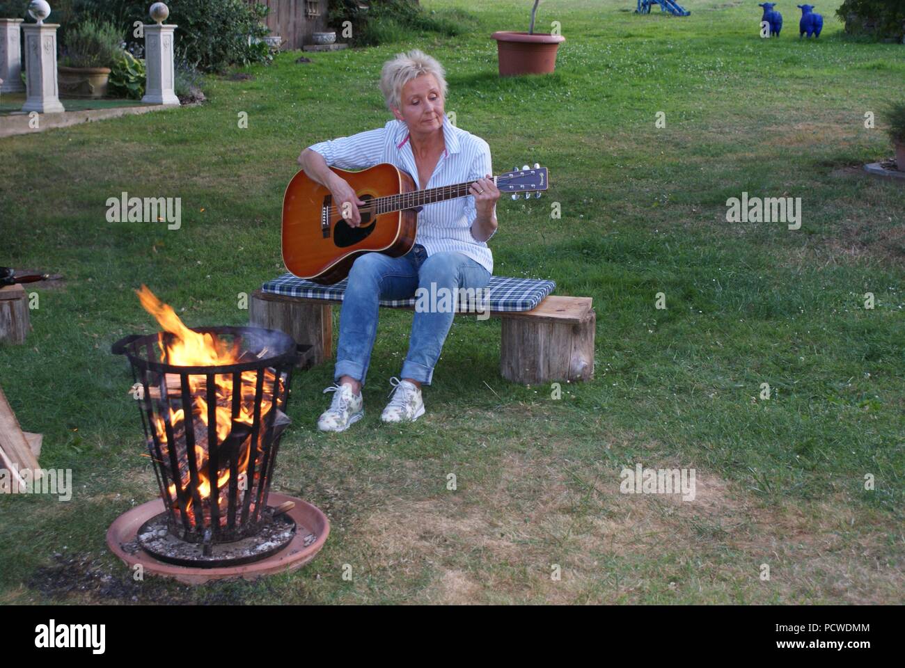 An einem schönen Sommerabend mit der Gitarre am Lagerfeuer Stockfoto