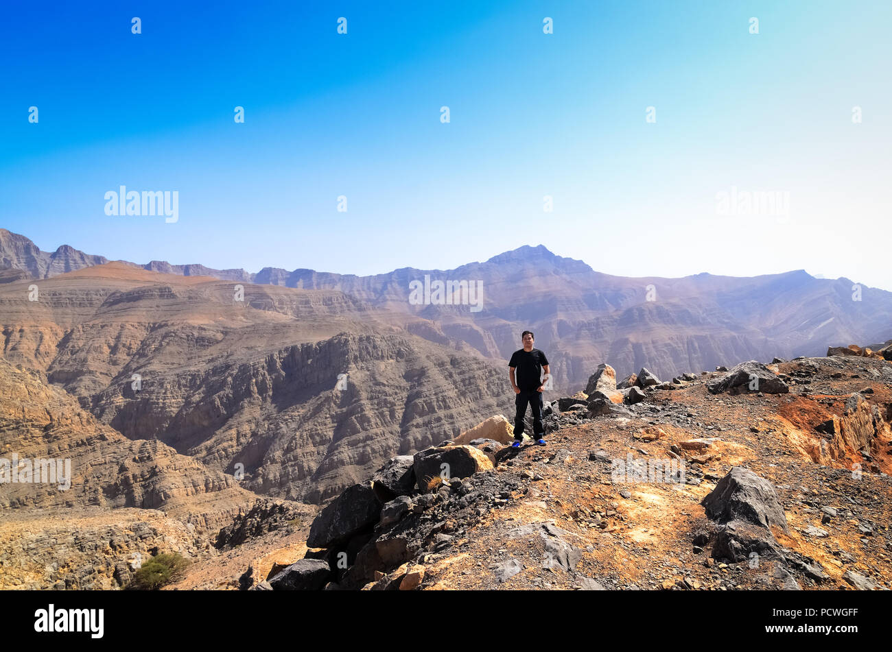 Ein Wanderer, die am Rand einer Klippe für ein Foto gestellt und genießen Sie die schöne Aussicht in Jebel Jais Berg in Ras Al Khaimah. Stockfoto