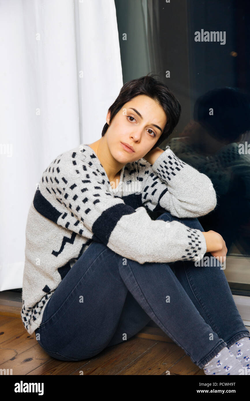 Traurige Frau sitzen auf dem Boden in der Ecke des Zimmers, Porträt eines traurigen Jugendmädchen suchen nachdenklich über Schwierigkeiten. Lonely depressiven Frau. Stockfoto