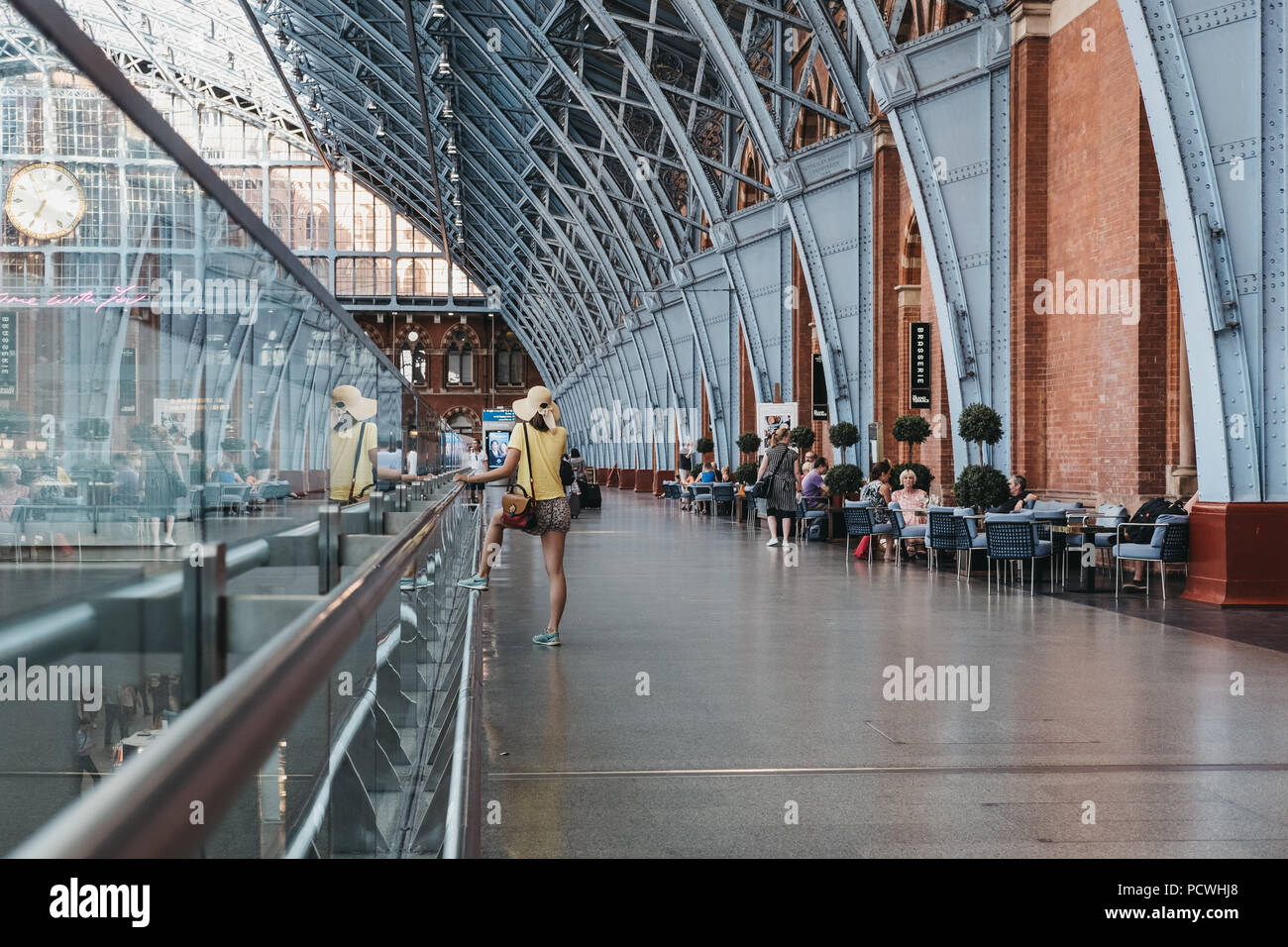 Nicht identifizierte Frau in einem gelben Top Telefonieren im Bahnhof St. Pancras, London, UK. Stockfoto