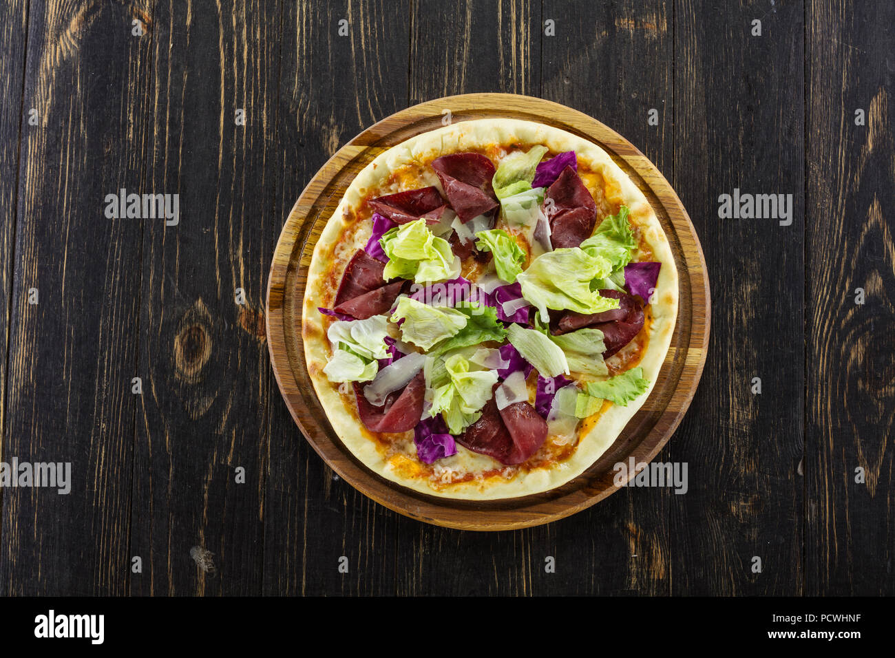 Pizza mit Fleisch und Gemüse auf Holzbrett, Ansicht von oben Stockfoto