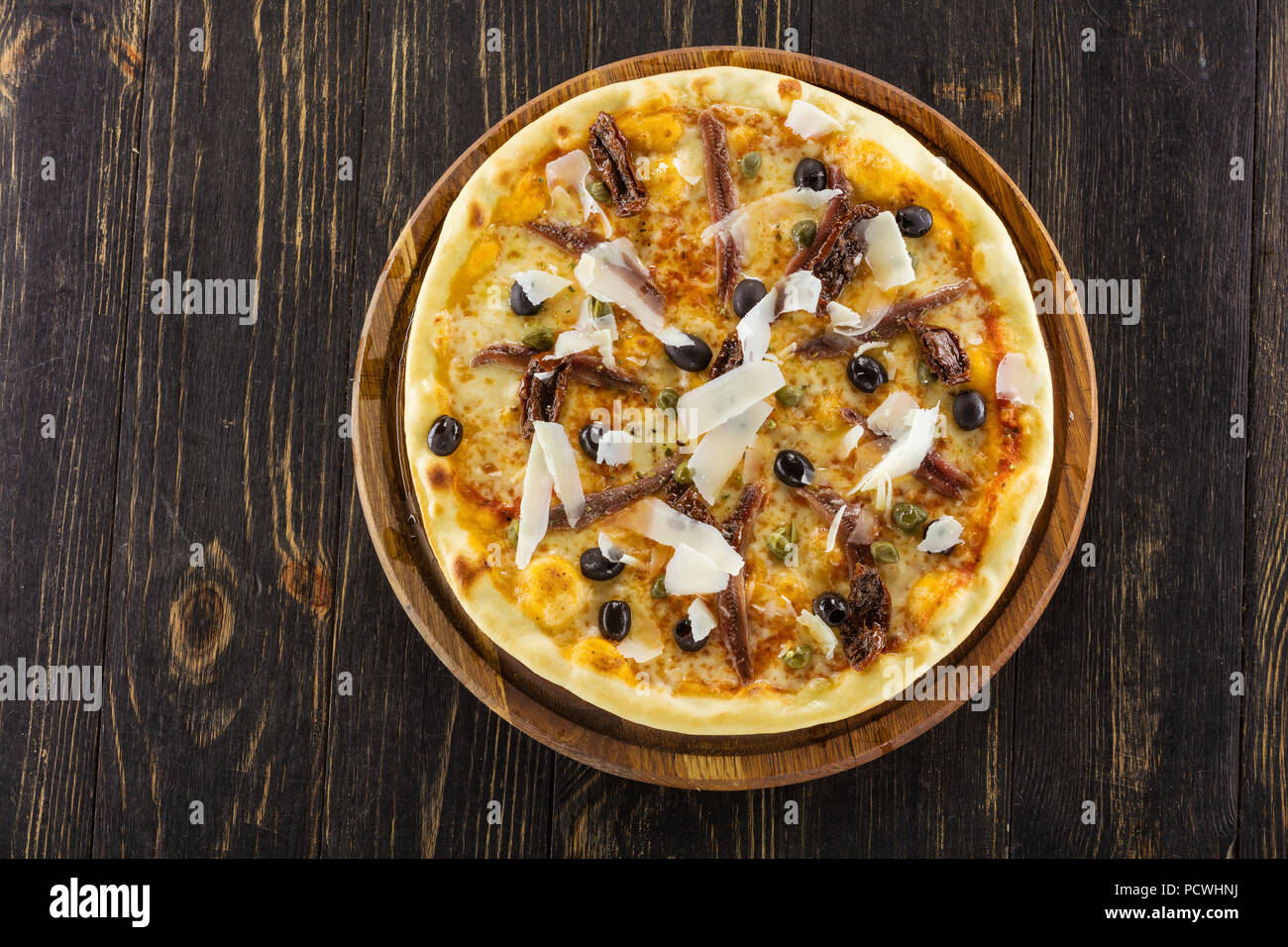 Sizilianische Pizza mit Sardellen und getrockneten Tomaten auf Holzbrett, Ansicht von oben Stockfoto