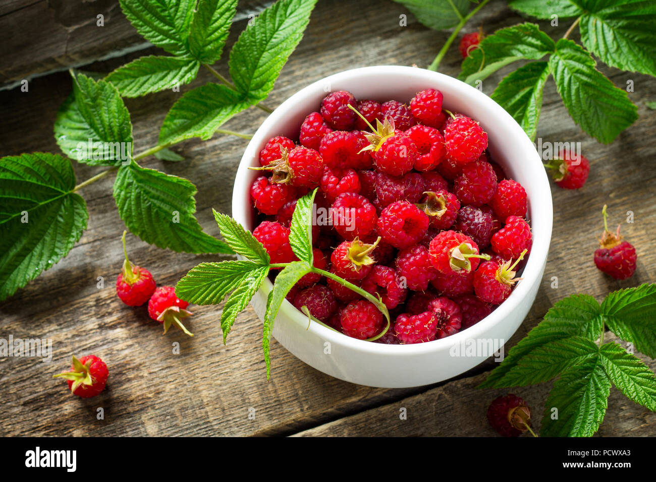 Frische süße Himbeeren in eine keramische Schüssel auf einen hölzernen Tisch. Das Konzept der Ernährung für Superfoods und Gesundheit oder Entgiftung. Stockfoto