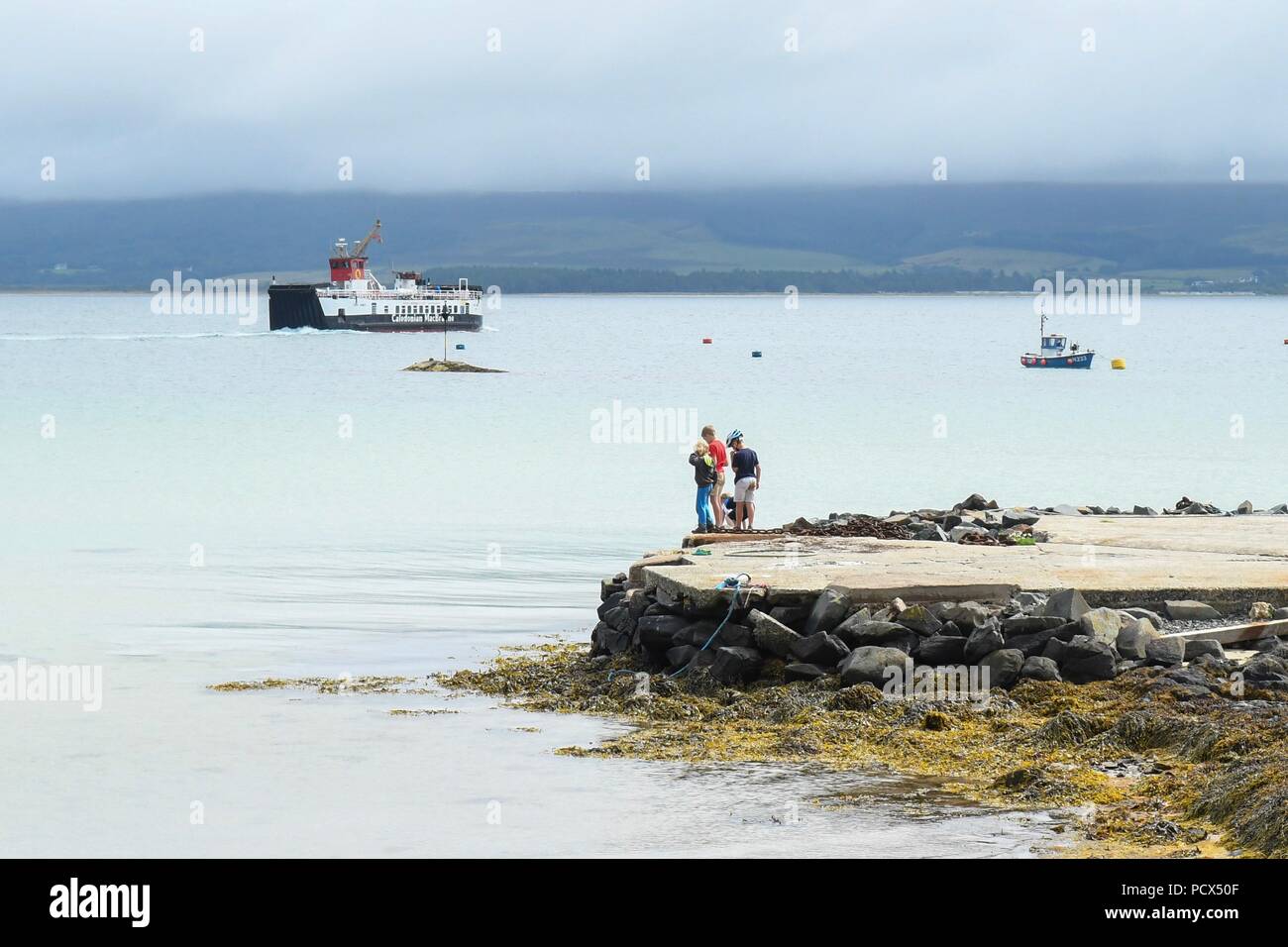 Gigha, Argyll, Schottland, Großbritannien - 4 August 2018: Britische Wetter - Kinder Angeln auf der Insel Gigha, einer kleinen Insel vor der Westküste von Kintyre, Argyll, Schottland als die Fähre vorbei auf dem Weg zurück zum Festland. Es ist noch warm, aber bewölkt mit sonnigen Perioden, kurze Schauer. Stockfoto