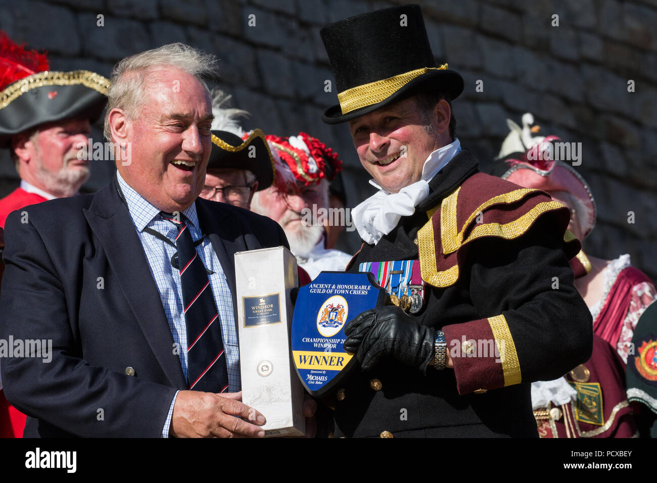 Windsor, Großbritannien. 4. August 2018. Christian Ashdown, Stadtausrufer von Haslemere, erhält den 1. Platz Award von Admiral Sir James Francis Kongress KBE, Constable und Gouverneur von Schloss Windsor, am Alten und ehrenvolle Gilde Town Criers (AHGTC) nationale Meisterschaft. 40 criers aus der ganzen Vereinigten Königreich und zwei aus Australien konkurrierten in zwei Runden von Weinen, die ersten, die ein Home Schrei auf Diktion, den Tonfall, die Klarheit und die Lautstärke und die zweite ein Schrei auf das Thema 'Feier' gezählt. Credit: Mark Kerrison/Alamy leben Nachrichten Stockfoto