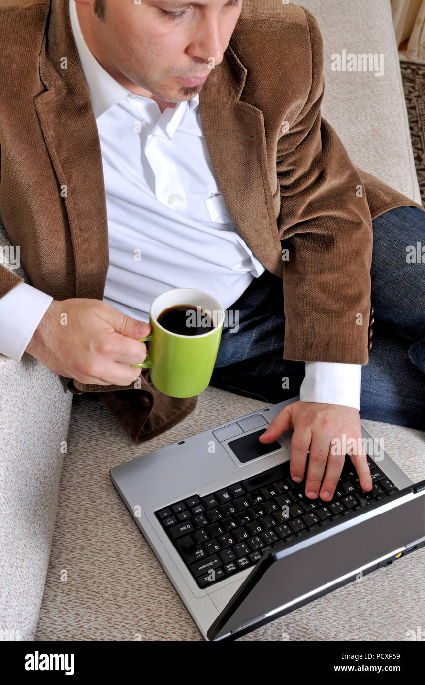 Workplace Konzept. Dienen friedlich ernste Büroangestellter Konzentration auf das Anschauen eines Videos über das Internet mit seinem Laptop und Tee trinken Vorsicht Stockfoto