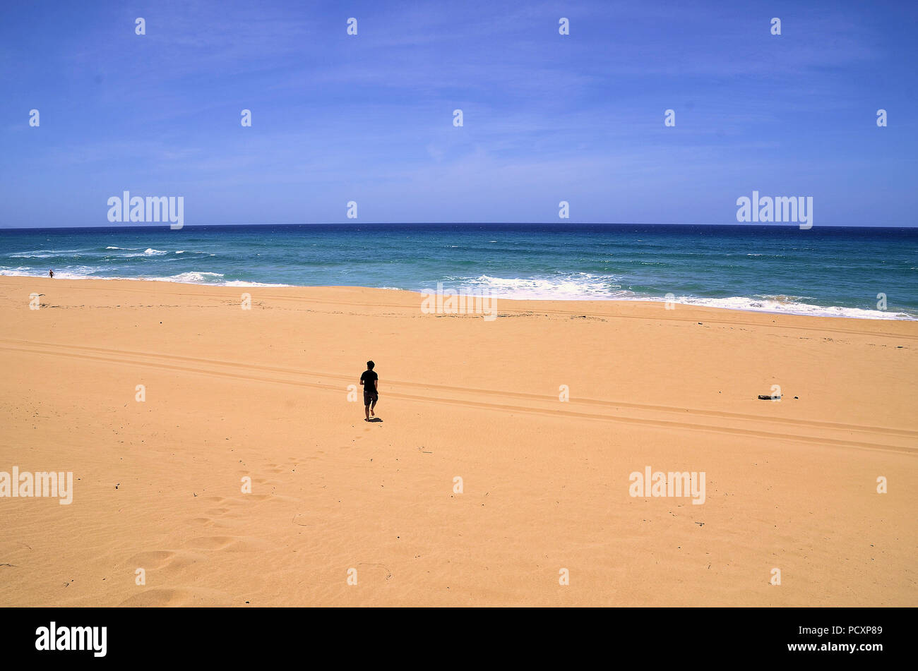 Einsame junge männliche Strand goer Joggt an den Rand des Wassers in den isolierten weißen Sandstrand an der Polihale State Park in Kauai, Hawaii, USA. Stockfoto