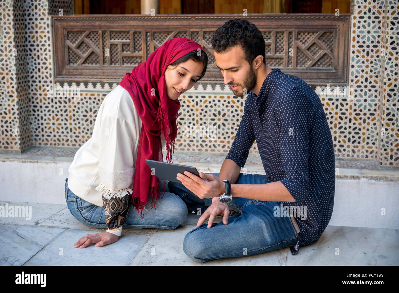 Junge muslimische Paare in Beziehung Lächeln während der Arbeit auf dem Tablet im traditionellen arabischen Ambient Stockfoto
