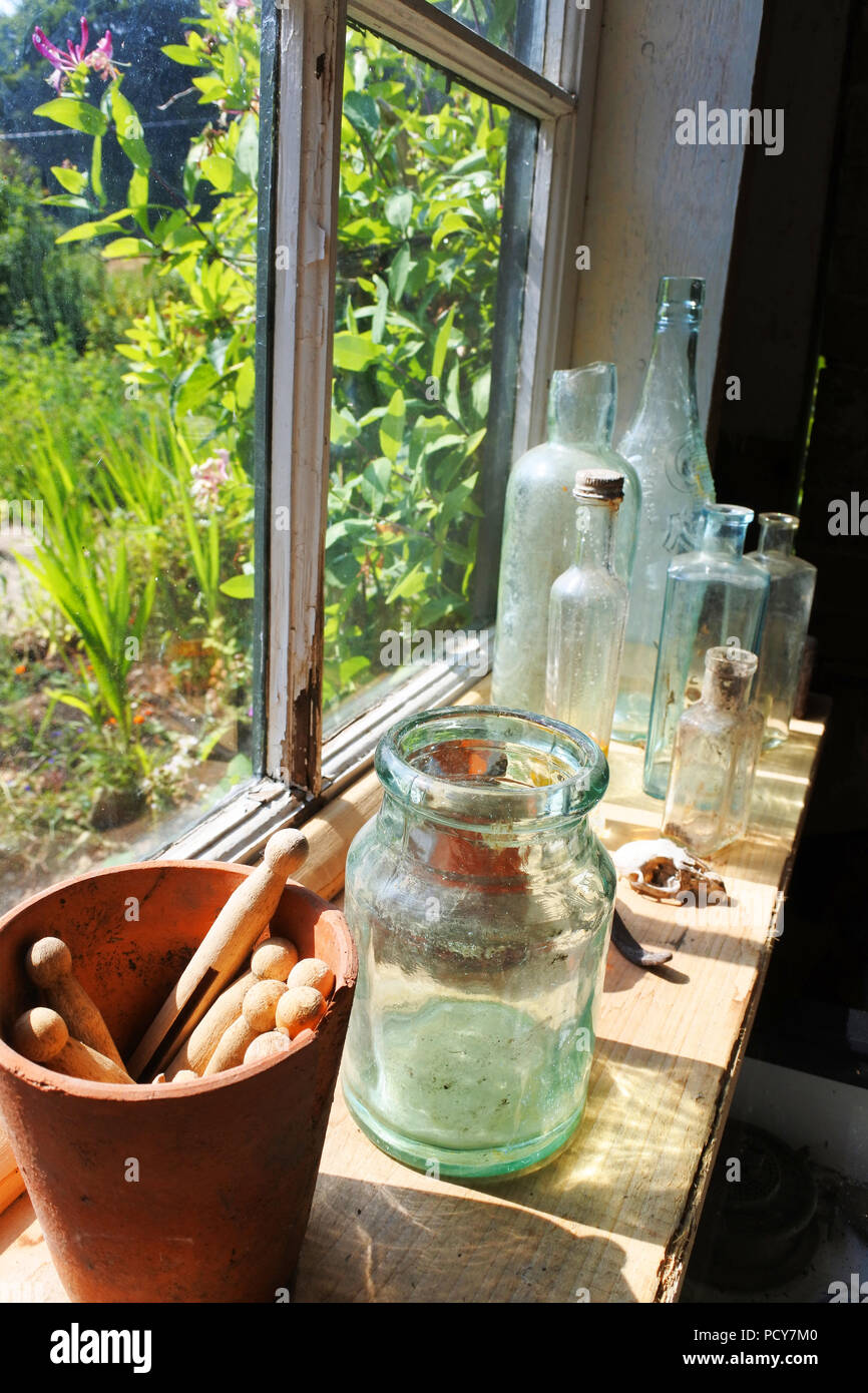 Flaschen, Gläsern und Wäscheklammern im Fenster einer alten Gartenhaus, England, UK-John Gollop Stockfoto