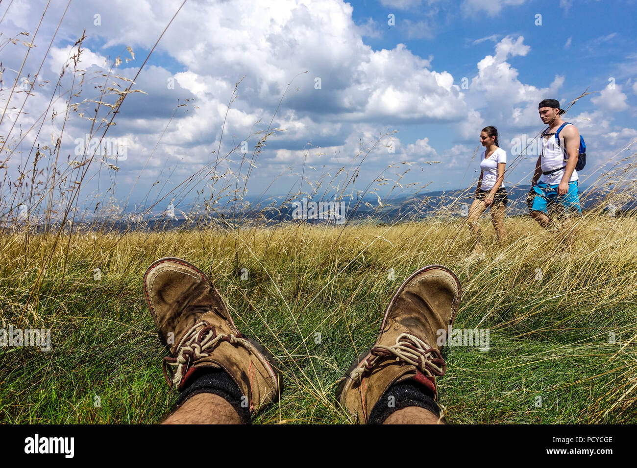 Wanderschuhe und Menschen, die auf einem Bergweg wandern, tschechische slowakische Grenze in Weißen Karpaten Blick auf die Stiefel und Füße eines Mannes, die im Gras ruhen Stockfoto