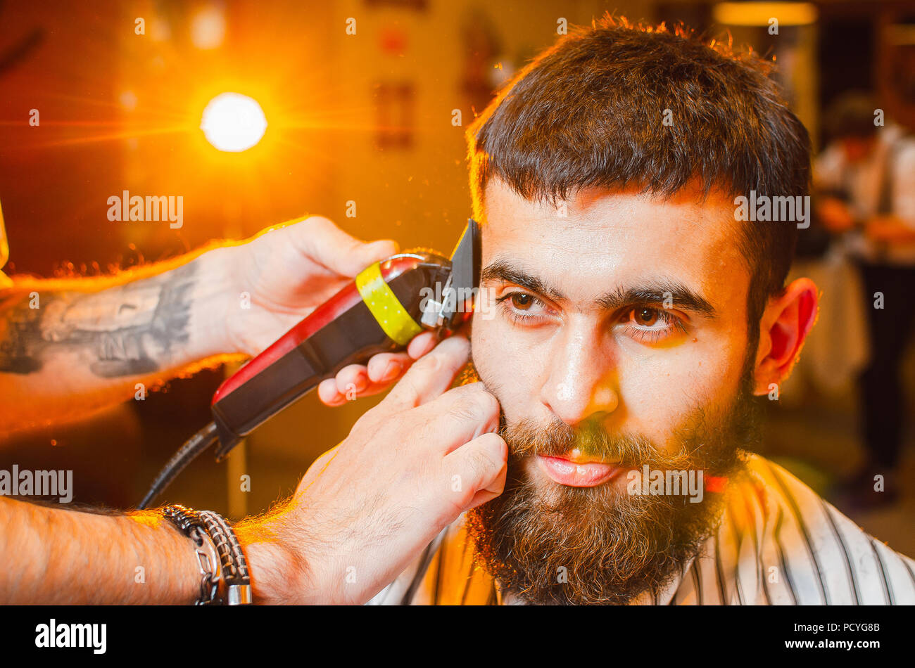 Friseur hat einen Haarschnitt auf seinem Kopf mit einem Langhaarschneider  auf ein junger hübscher Kerl mit einem Schnurrbart und Bart. Herren  Friseursalon Stockfotografie - Alamy